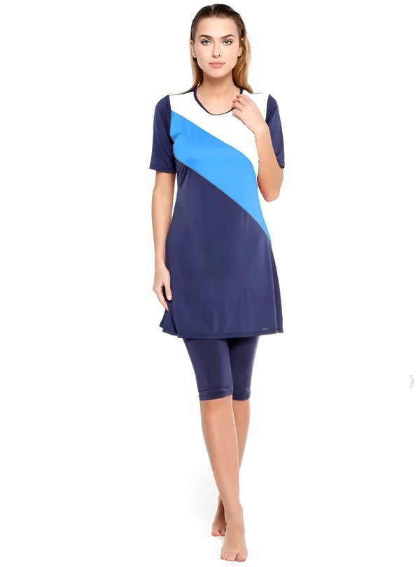 Une femme portant un maillot de bain musulman bleu foncé, blanc et bleu clair avec des manches courtes et des leggings.