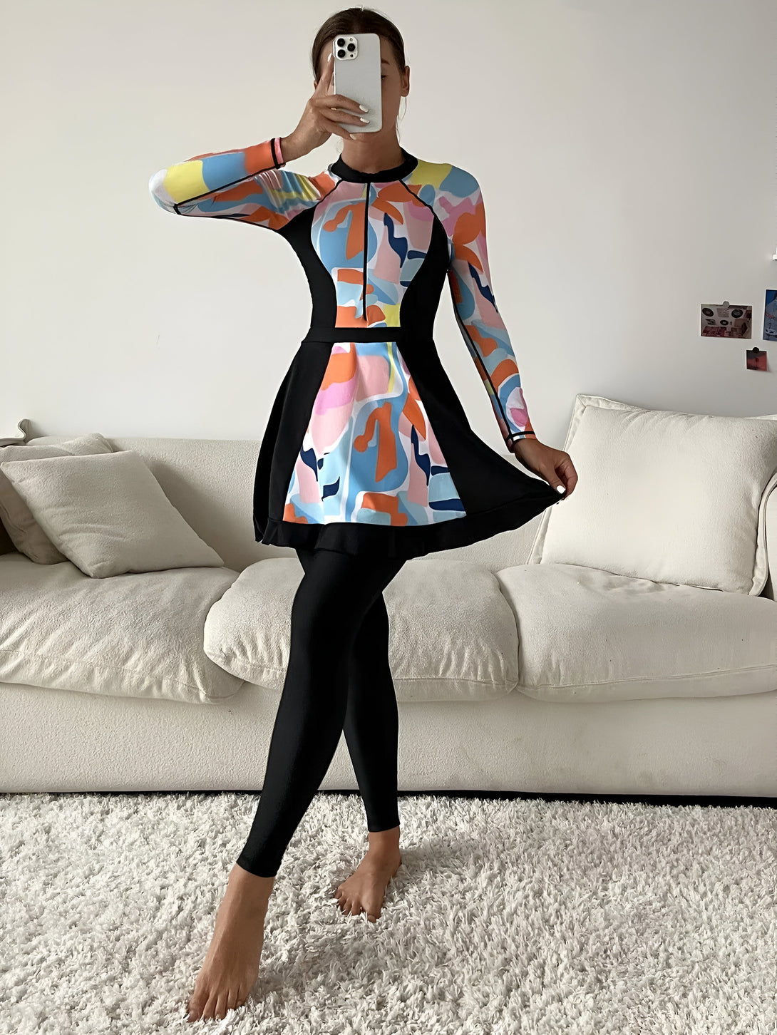 Une femme portant une robe de bain musulmane à manches longues avec un motif coloré et des leggings noirs.