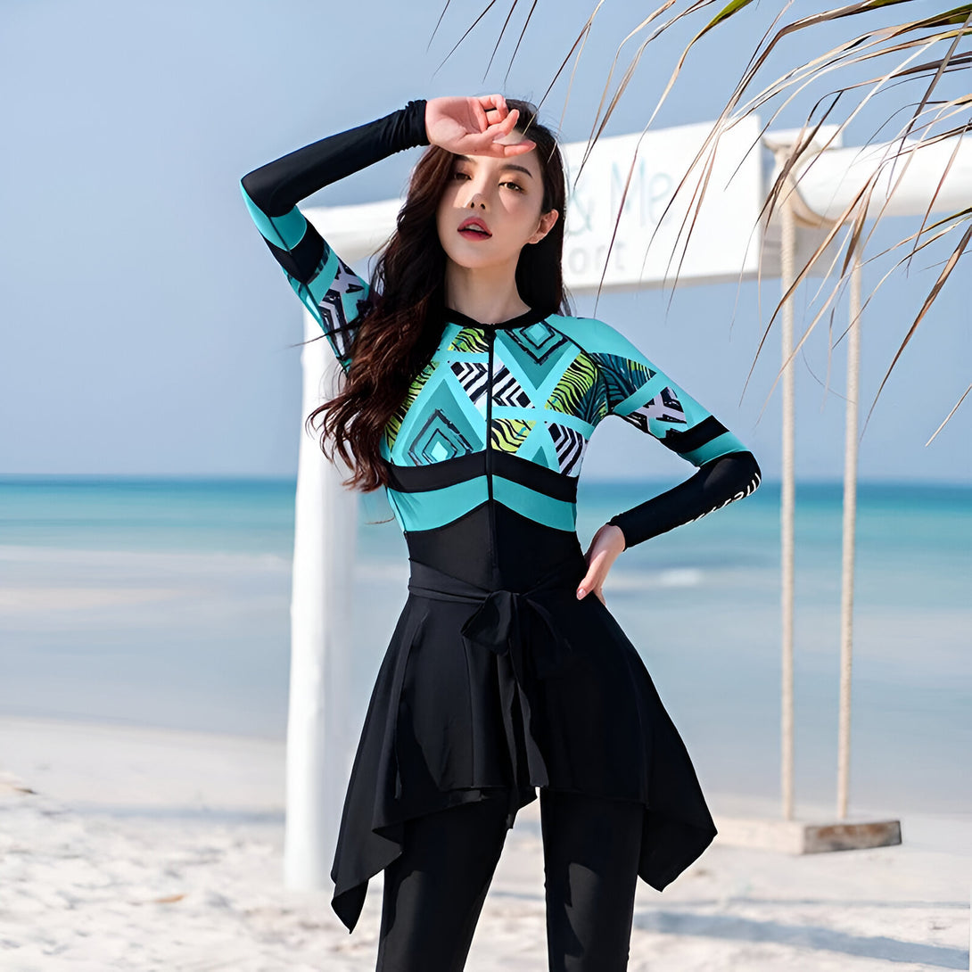 Une femme portant un maillot de bain islamique bleu turquoise et noir avec des motifs géométriques et animaliers.