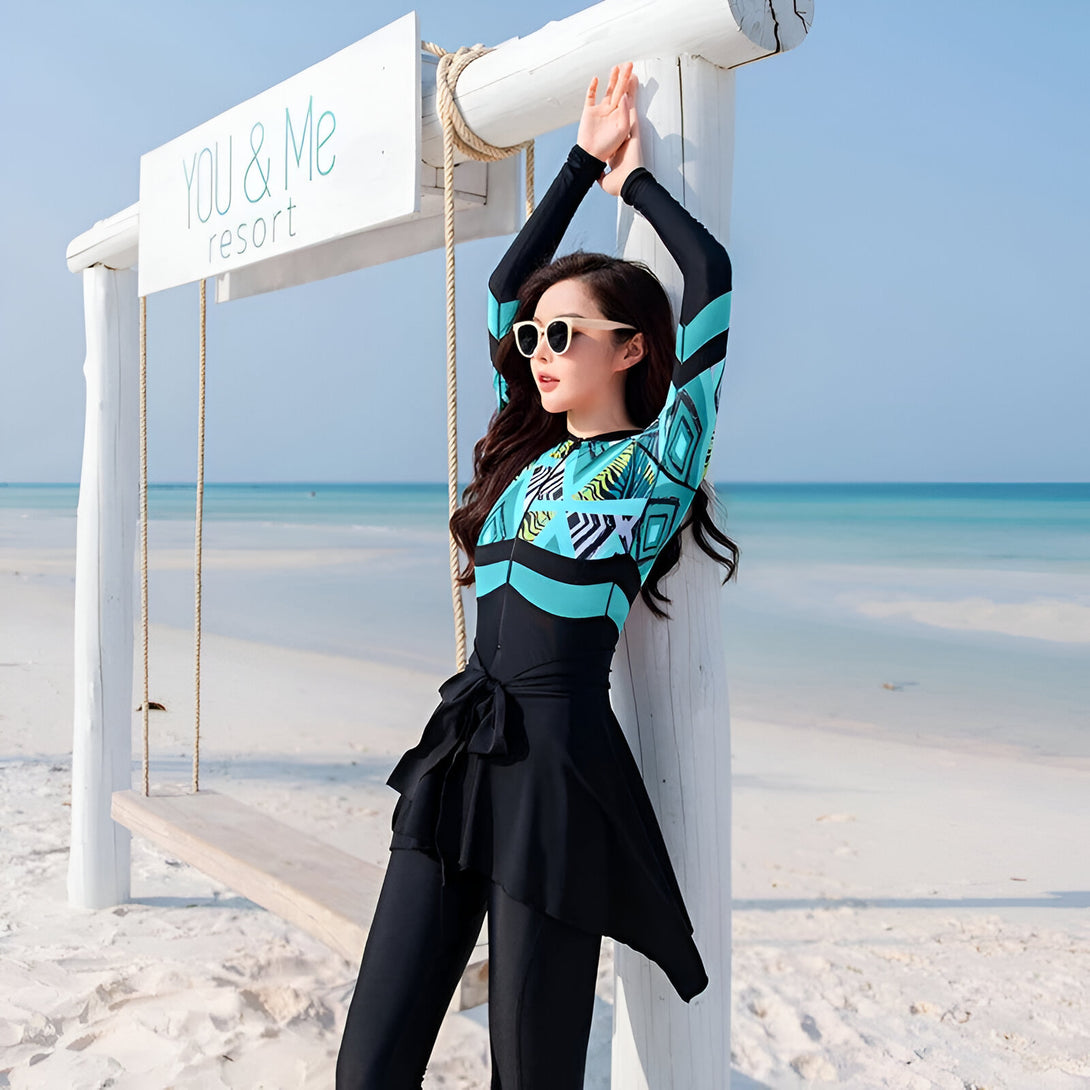 Une femme portant un maillot de bain musulman bleu et noir avec un motif géométrique sur la plage.