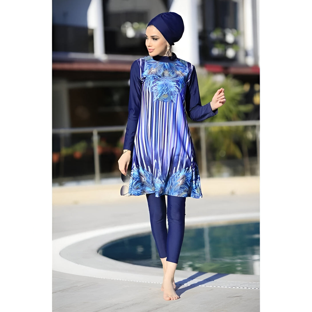 Une femme portant un hijab bleu et un maillot de bain musulman bleu à rayures et motifs floraux. Elle pose près d'une piscine.