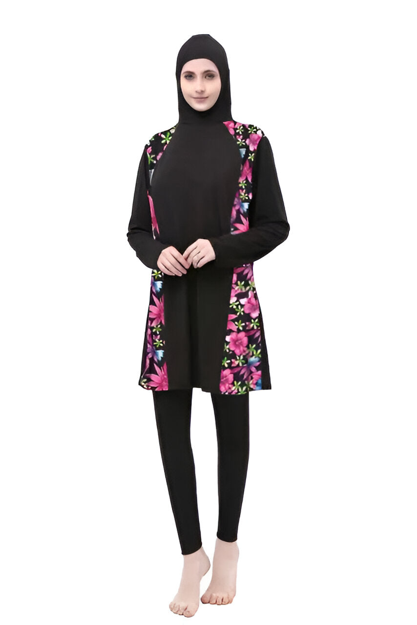 Une femme portant un maillot de bain musulman noir avec des fleurs roses et bleues. Le maillot de bain est à manches longues et couvre tout le corps.