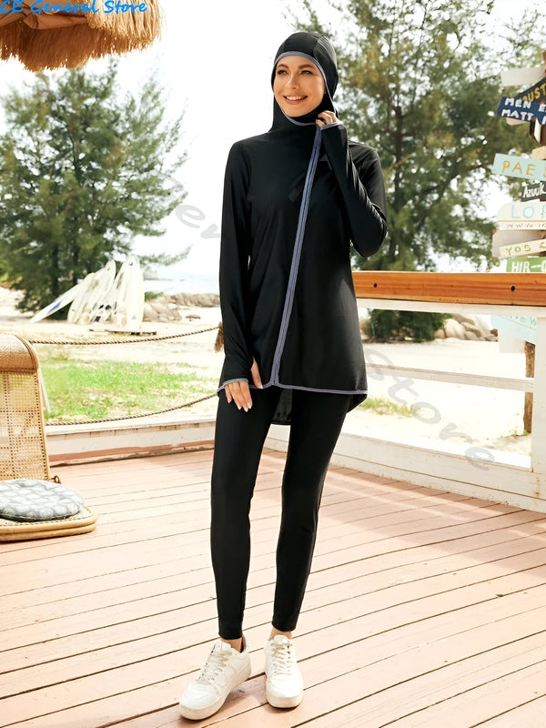 Une femme portant un hijab noir et un maillot de bain musulman noir avec des détails gris à l'extérieur d'un restaurant de plage.