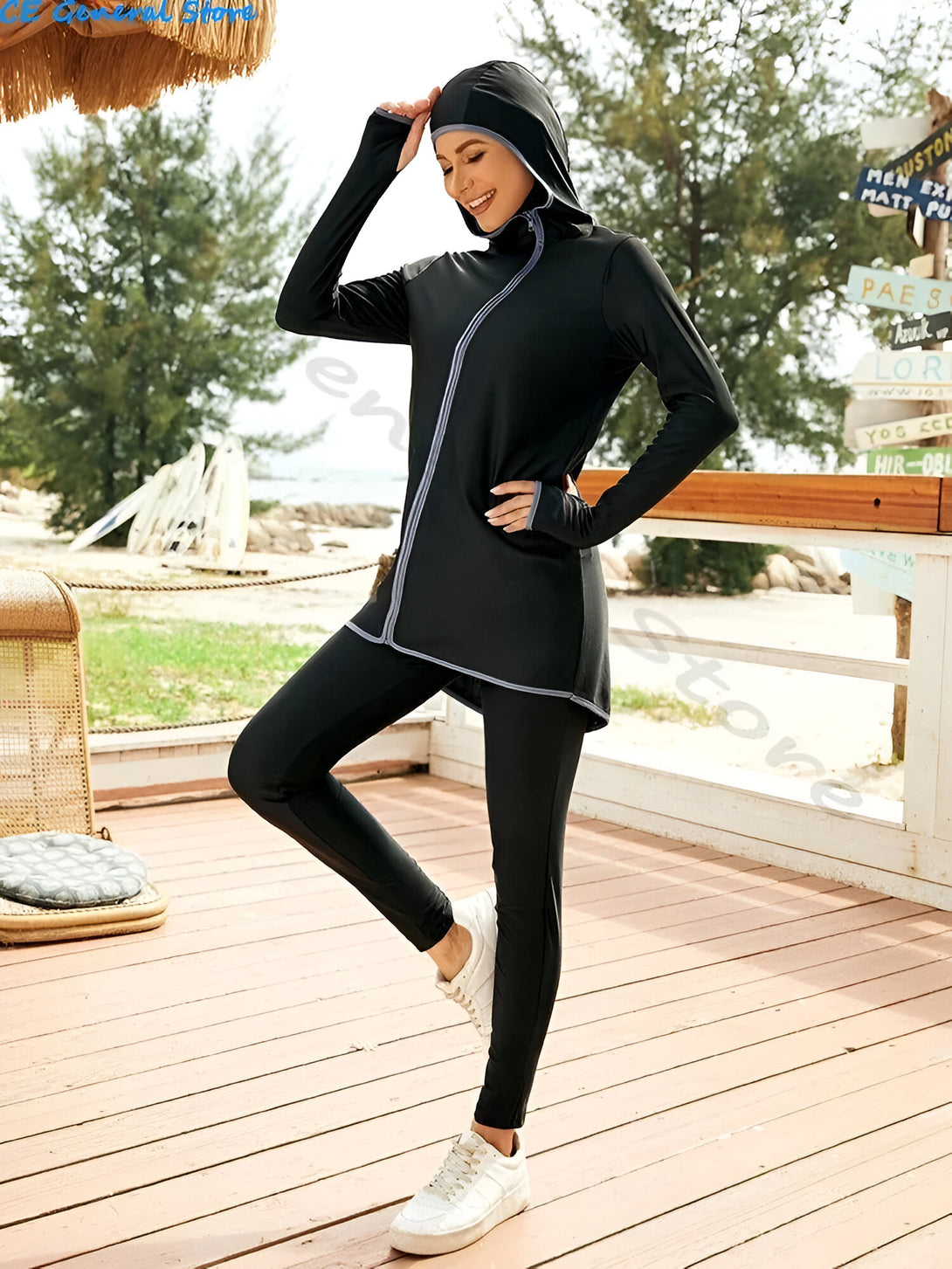 Une femme portant un hijab noir et un ensemble de vêtements de plage musulmans noirs avec une fermeture éclair et des détails gris.