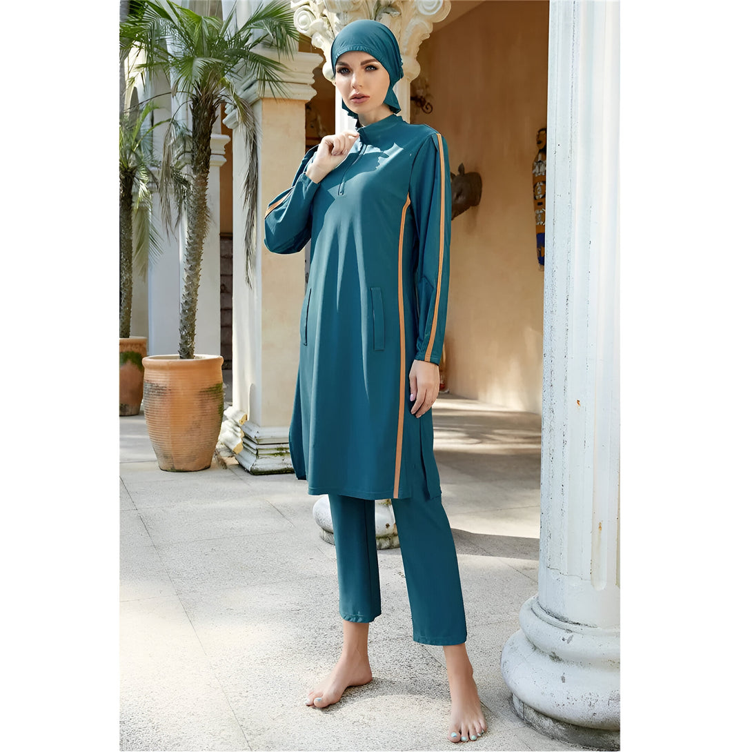 Une femme portant un maillot de bain musulman vert avec des rayures orange. Le maillot de bain comprend une tunique longue et un pantalon.