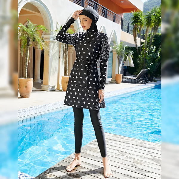 Une femme portant un maillot de bain musulman noir et blanc à motifs géométriques, debout près d'une piscine.