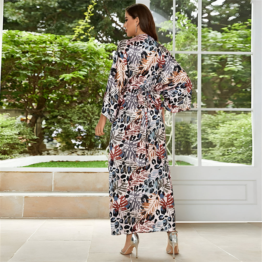 Une femme porte une longue robe musulmane à imprimé floral et léopard. La robe est à manches longues et a une ceinture à la taille. Elle porte des talons argentés.