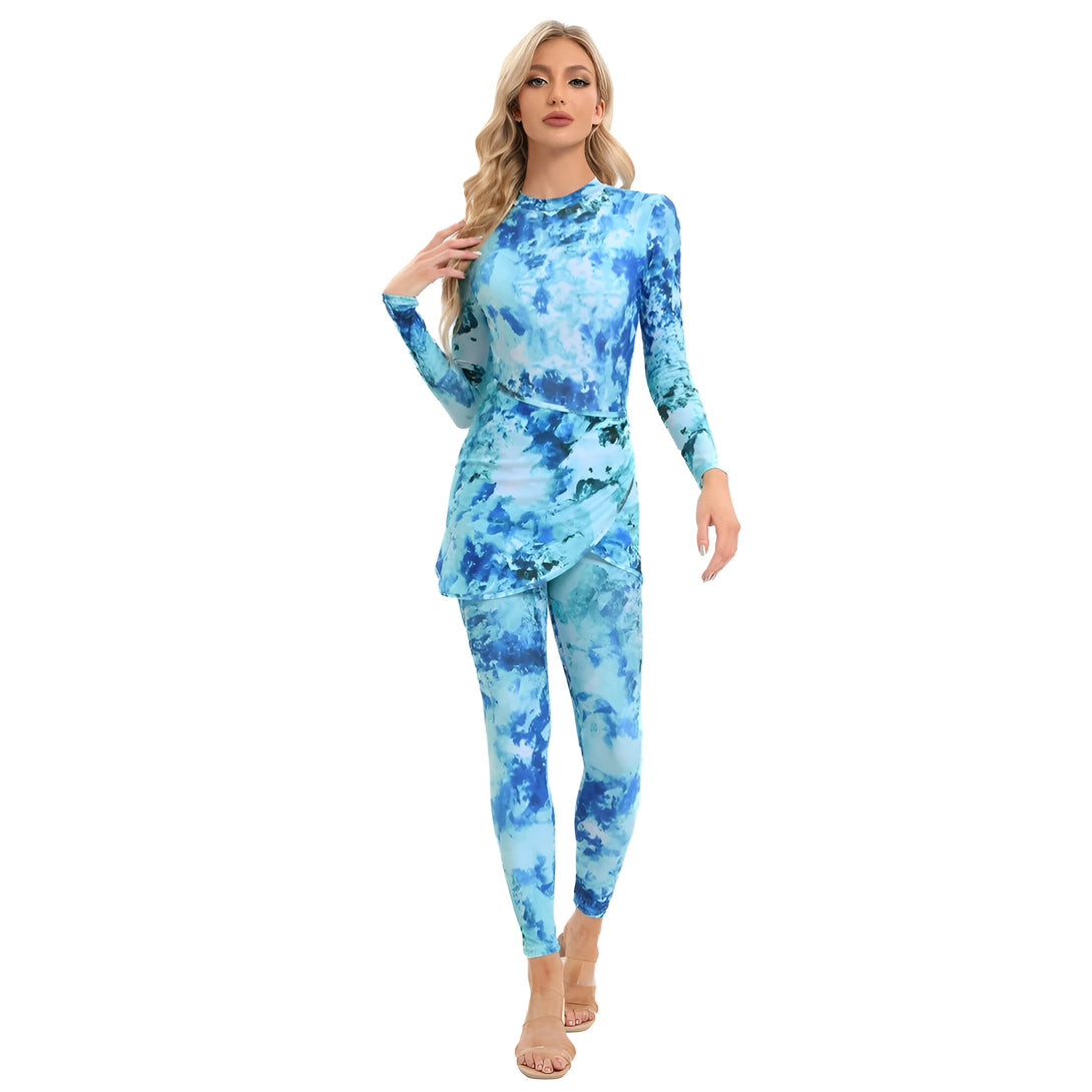 Une femme portant une tenue de bain musulmane bleue à imprimé tie-dye avec un pantalon et un haut à manches longues.