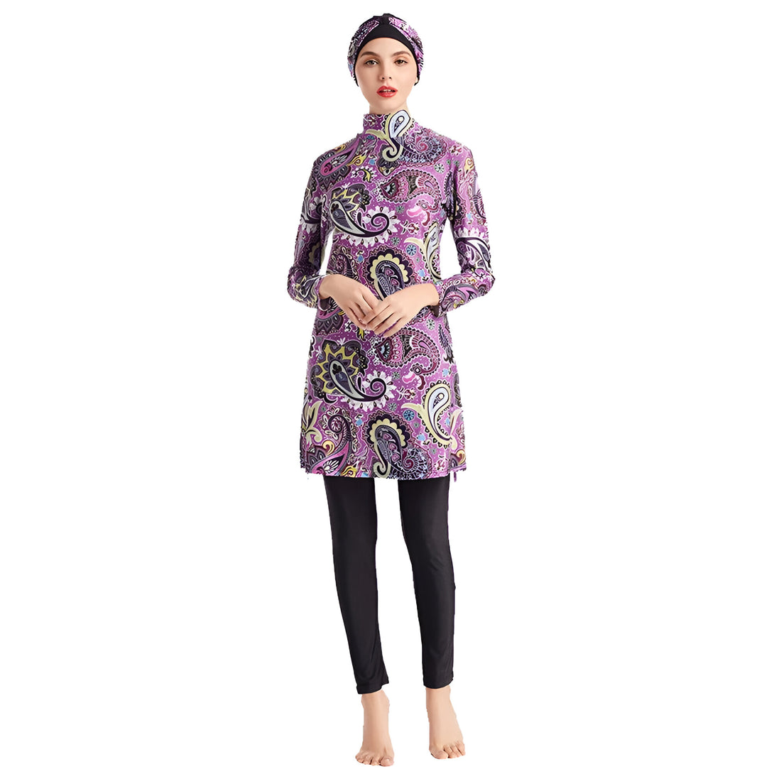 Une femme portant un maillot de bain musulman avec un motif paisley violet. Le maillot de bain comprend un haut à manches longues et un pantalon long. La femme porte également un hijab noir.