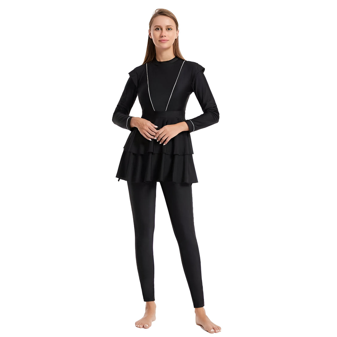 Une femme portant un maillot de bain musulman noir avec une jupe à volants. Le maillot de bain a des manches longues et des jambes longues.