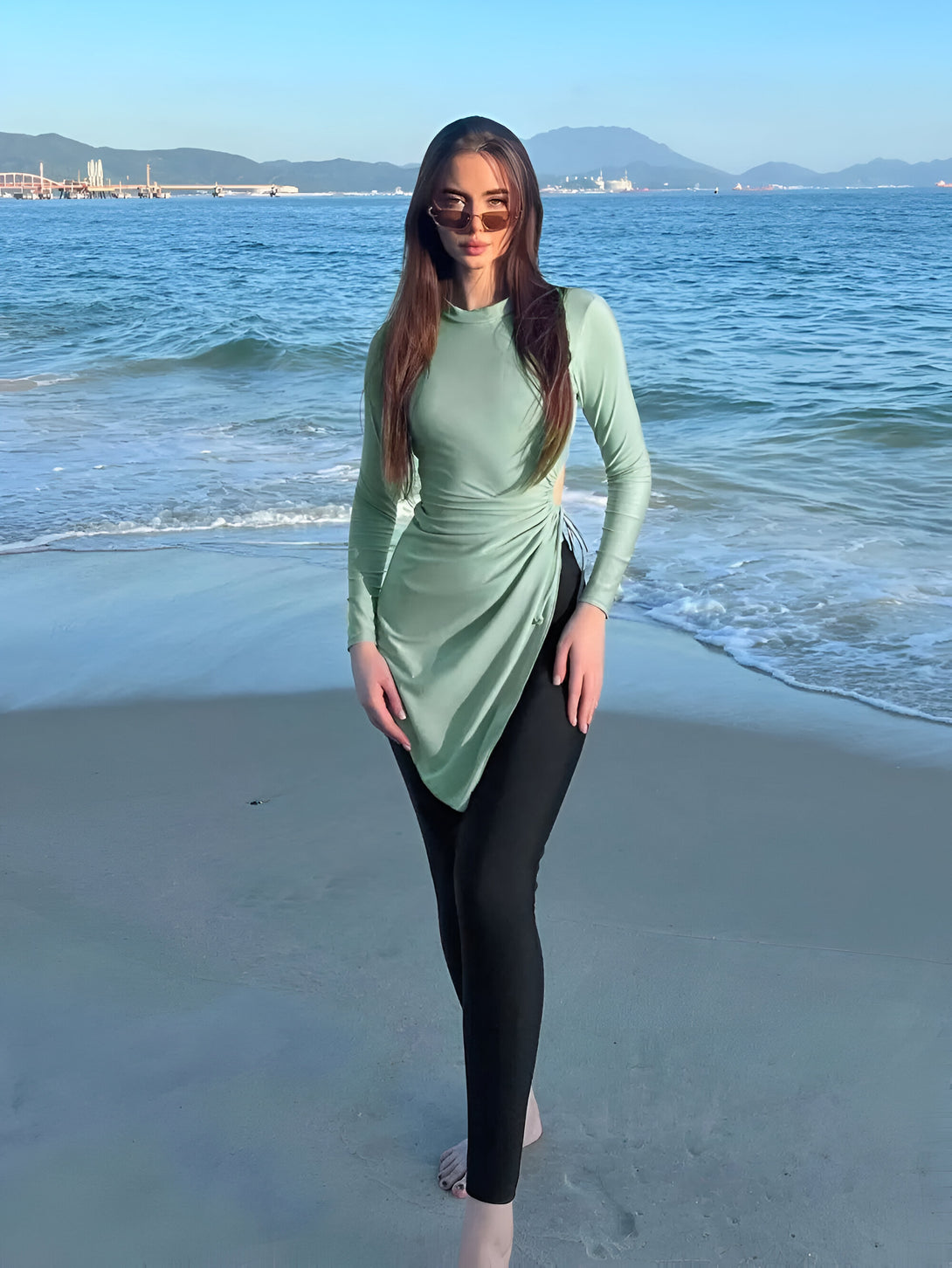 Une femme portant un maillot de bain islamique vert sur la plage.