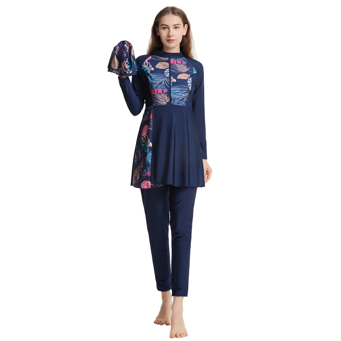 Une femme porte un maillot de bain musulman bleu marine avec un imprimé floral. Le maillot de bain est composé d'une tunique à manches longues et d'un pantalon long. La femme porte également un hijab assorti.