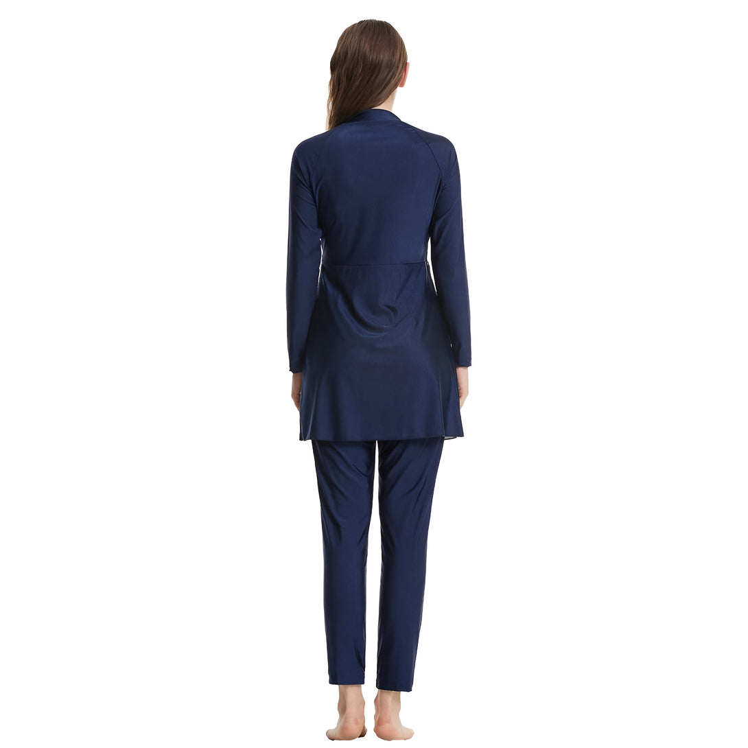 Une femme portant un maillot de bain musulman bleu foncé avec manches longues et pantalon long. Le maillot est conçu pour couvrir tout le corps.