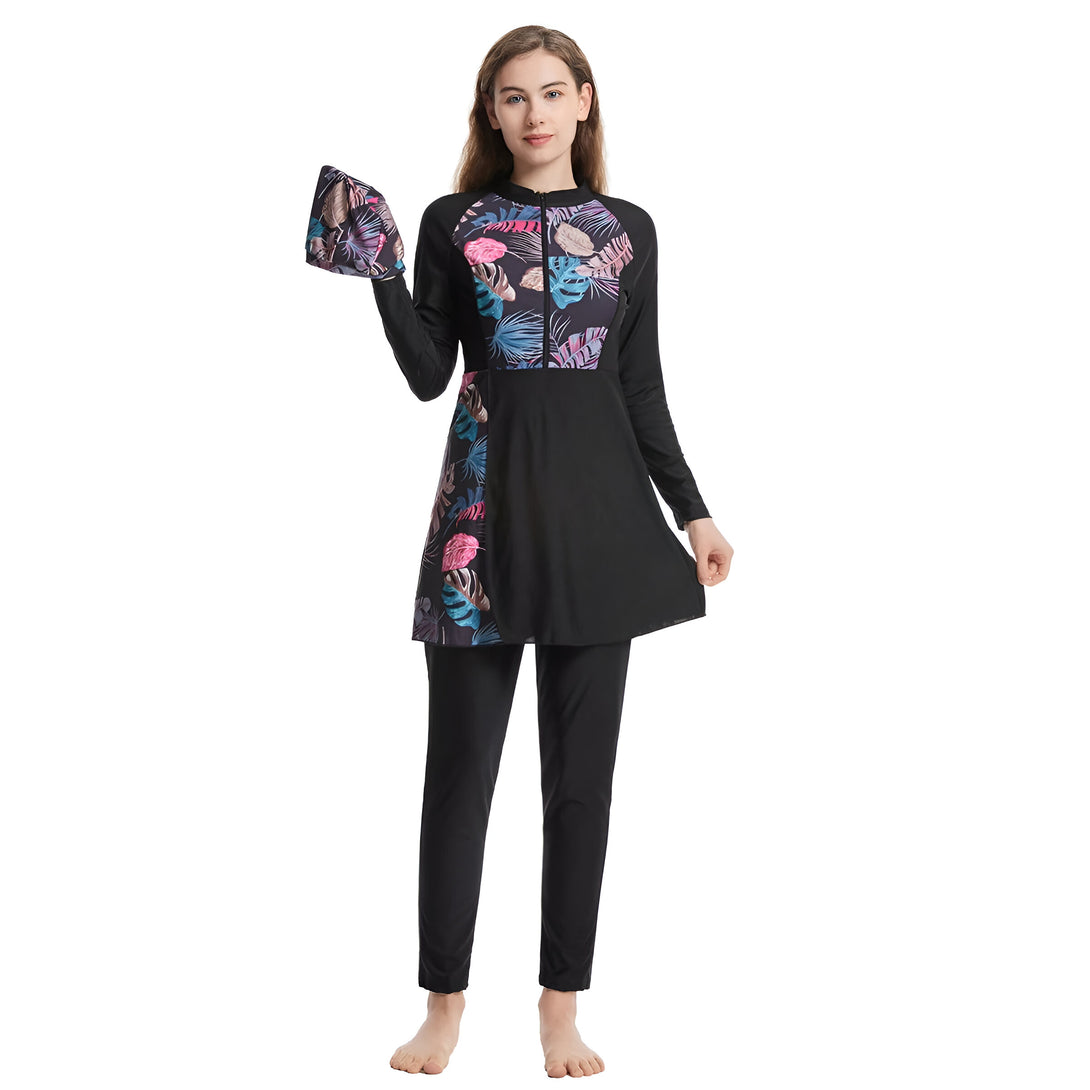 Une femme porte un maillot de bain musulman noir avec des imprimés floraux. Le maillot de bain comprend une tunique à manches longues et un pantalon long. Le hijab assorti est inclus.