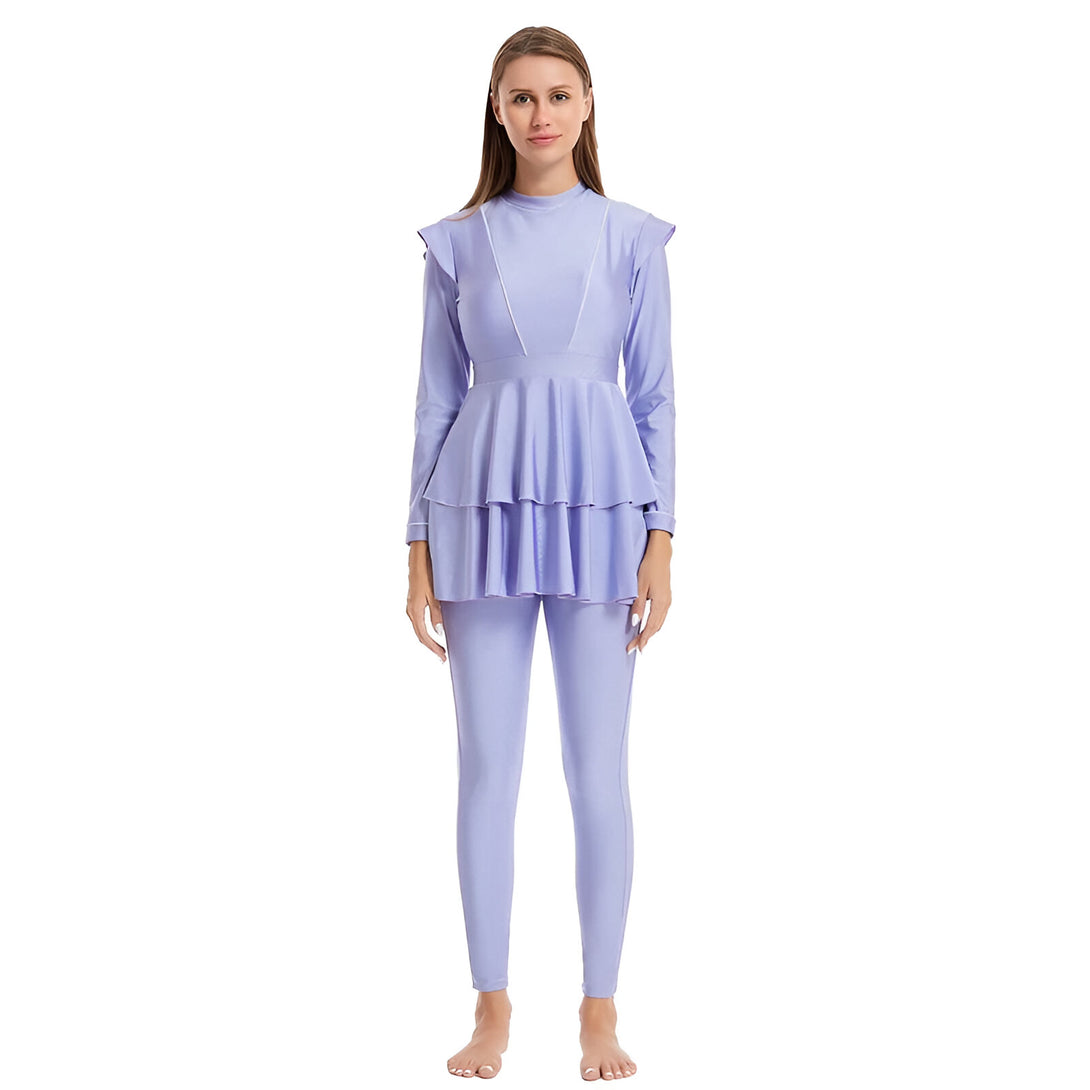 Une femme portant un maillot de bain islamique violet à manches longues et un pantalon long. La tenue est à la fois modeste et élégante, idéale pour les femmes musulmanes qui souhaitent profiter du soleil et de la plage.