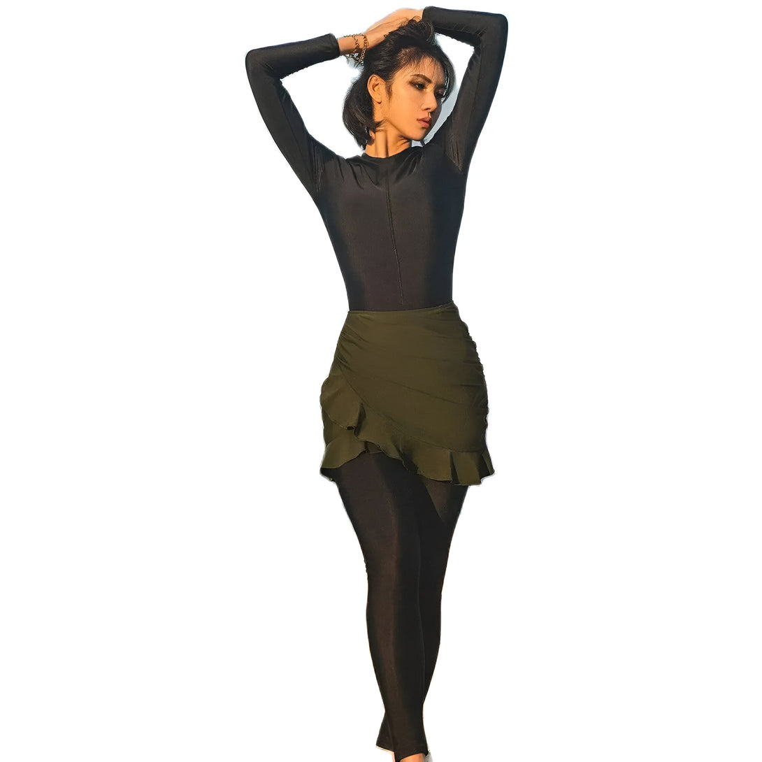 Une femme portant une tenue de bain musulmane noire à manches longues et une jupe verte à volants.