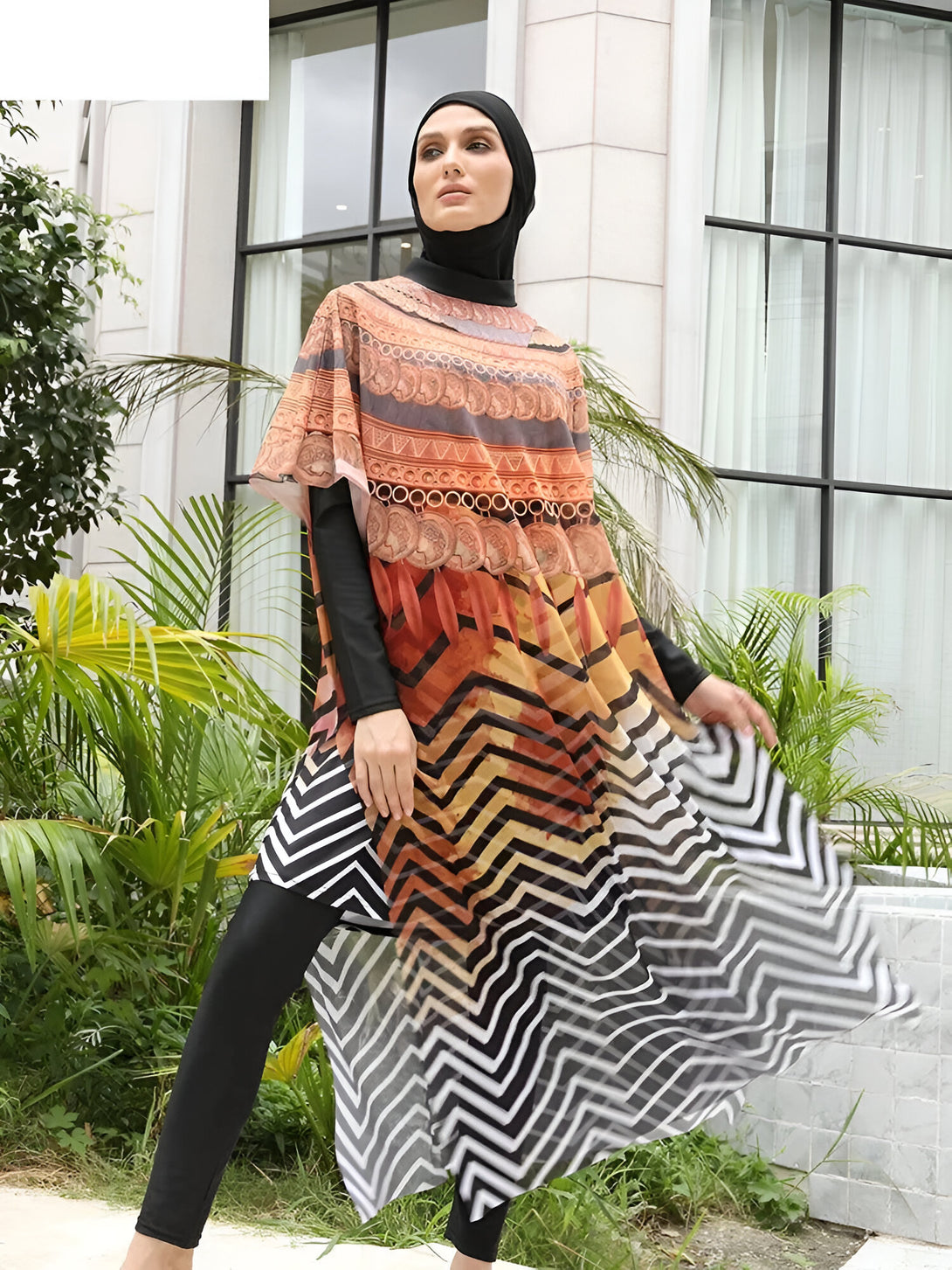Une femme portant un hijab et une robe de bain musulmane à motifs géométriques orange et noir.