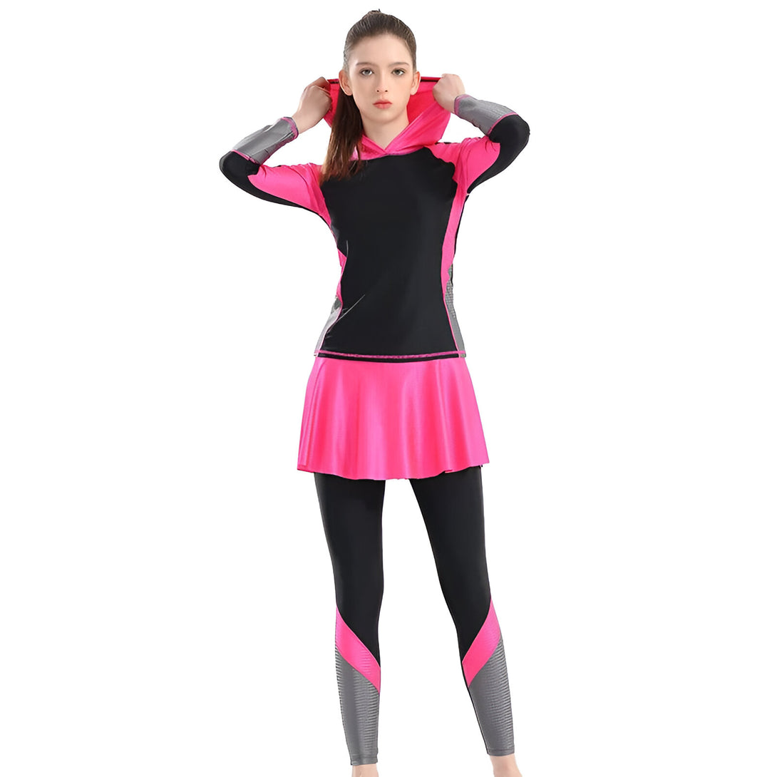 Une femme portant un ensemble de vêtements musulmans composé d'un haut à manches longues avec une capuche, d'une jupe et d'un pantalon. L'ensemble est noir et rose.