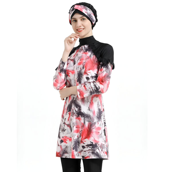 Une femme souriante portant un hijab noir et une robe de bain musulmane à manches longues avec un imprimé de plumes rouge et noir.