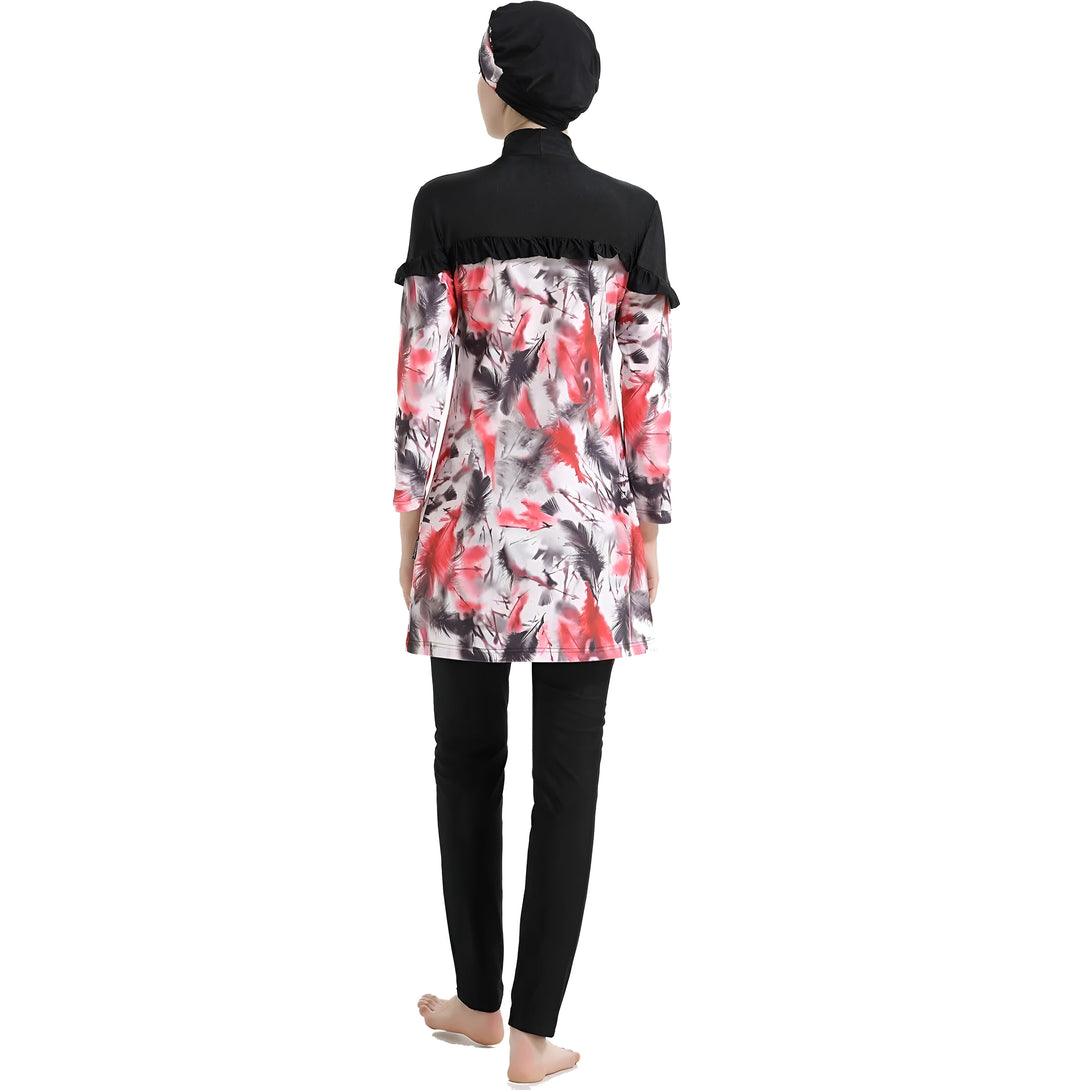 Une femme portant un maillot de bain musulman à manches longues avec un motif rouge et noir. Le maillot de bain est composé d'une tunique et d'un pantalon long. La femme porte également un foulard noir.