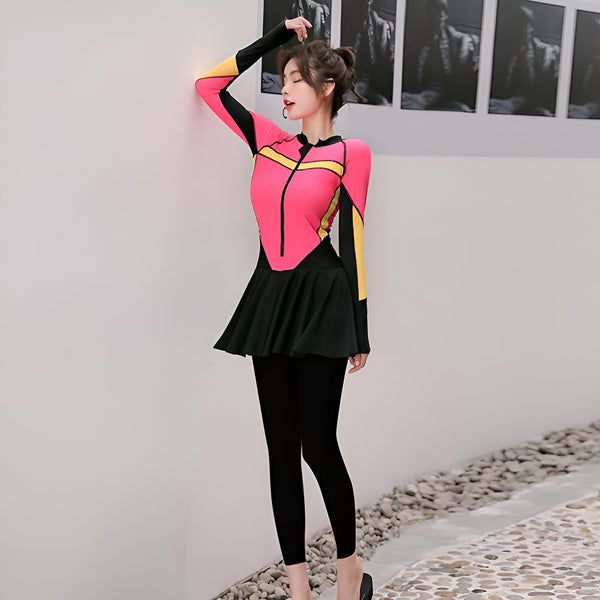 Une femme portant un maillot de bain islamique rose avec des détails jaunes et noirs, une jupe noire et des leggings noirs.  La tenue est parfaite pour nager et bronzer tout en respectant les traditions islamiques.