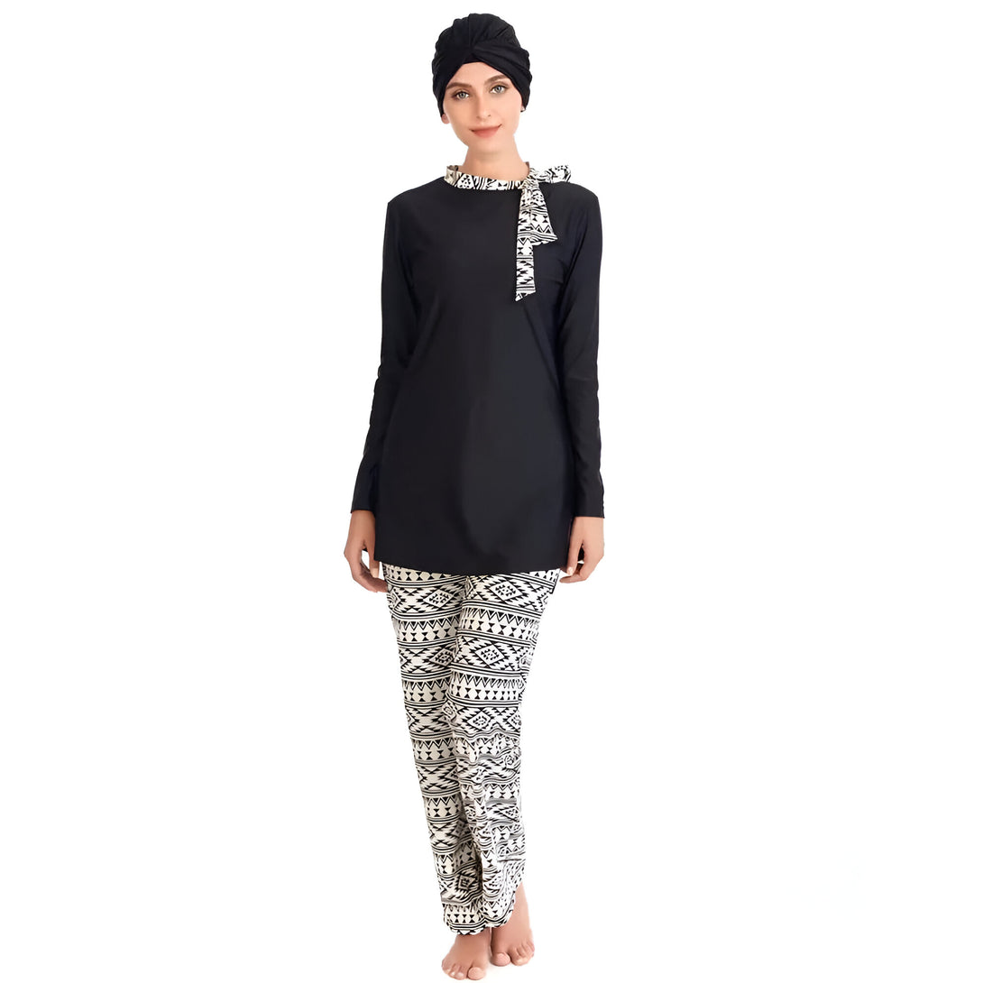 Une femme portant un hijab noir et un maillot de bain musulman noir et blanc avec un pantalon à motifs géométriques.