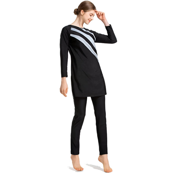 Une femme portant un maillot de bain musulman noir avec des rayures blanches. Le maillot de bain est à manches longues et couvre les jambes. La femme sourit et regarde vers le bas.