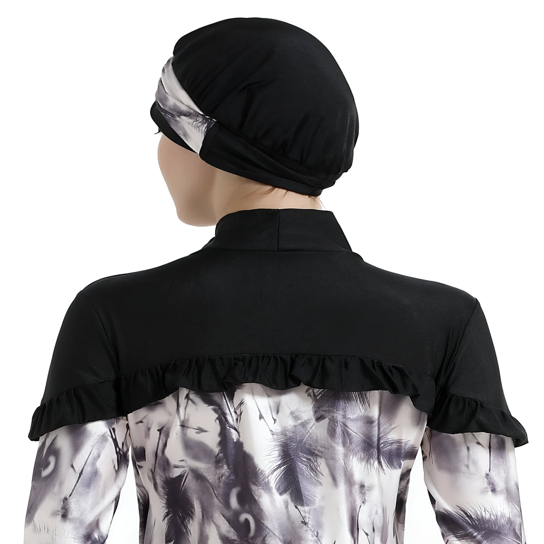 Une femme portant un hijab noir et une robe musulmane à motif de plumes grises sur fond blanc.