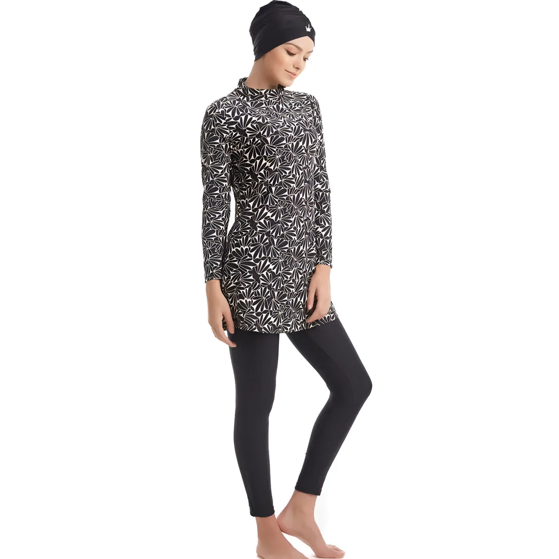 Une femme portant un maillot de bain musulman noir et blanc à fleurs avec un hijab noir.