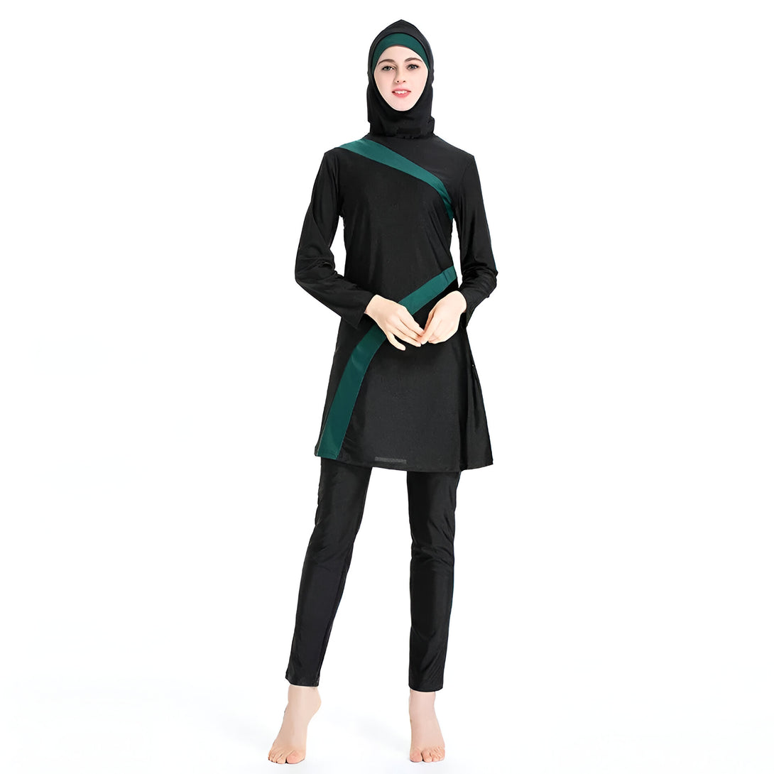 Une femme portant un maillot de bain musulman noir avec des accents verts. Le maillot de bain est long et couvre tout le corps, y compris les bras et les jambes. La femme porte également un hijab noir.