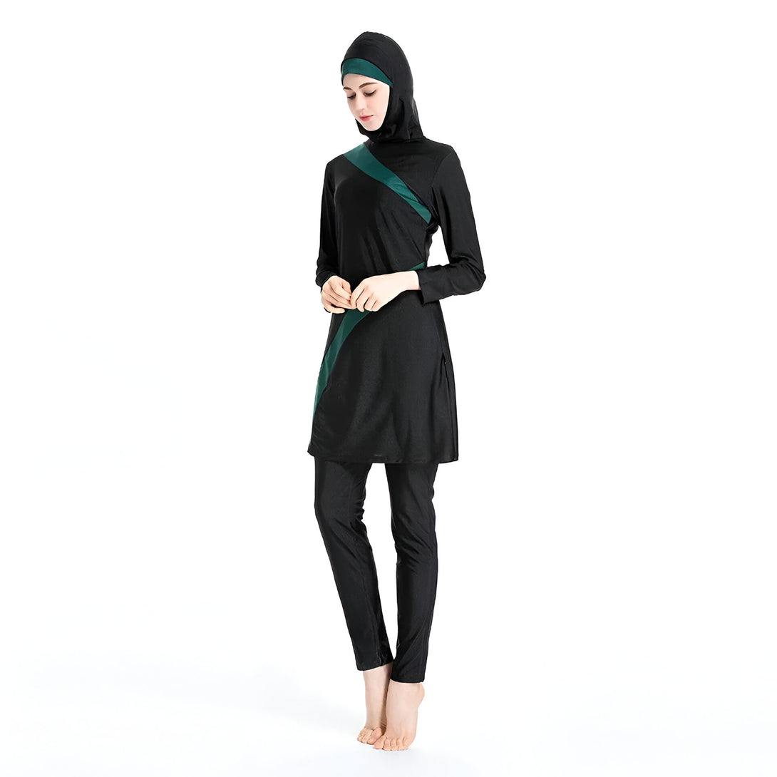 Une femme portant un maillot de bain musulman noir avec des détails verts. Le maillot de bain est à manches longues et comprend un pantalon long.