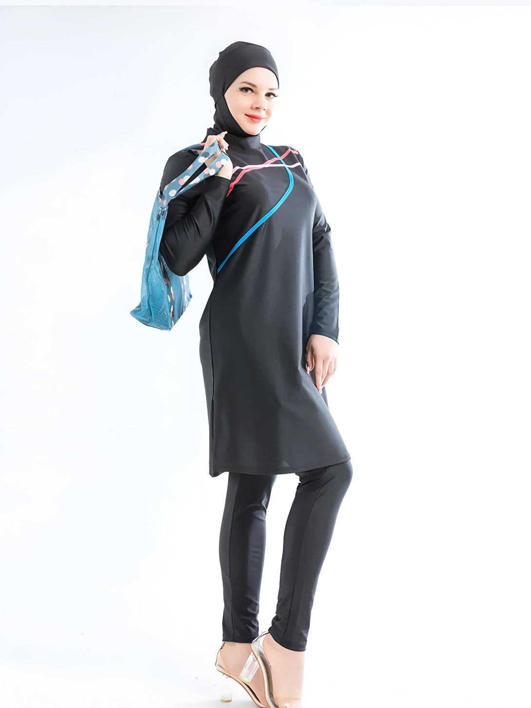 Une femme portant un maillot de bain musulman noir avec des détails colorés, tenant un sac à main bleu.  Elle porte un hijab noir et des chaussures à talons hauts transparentes.