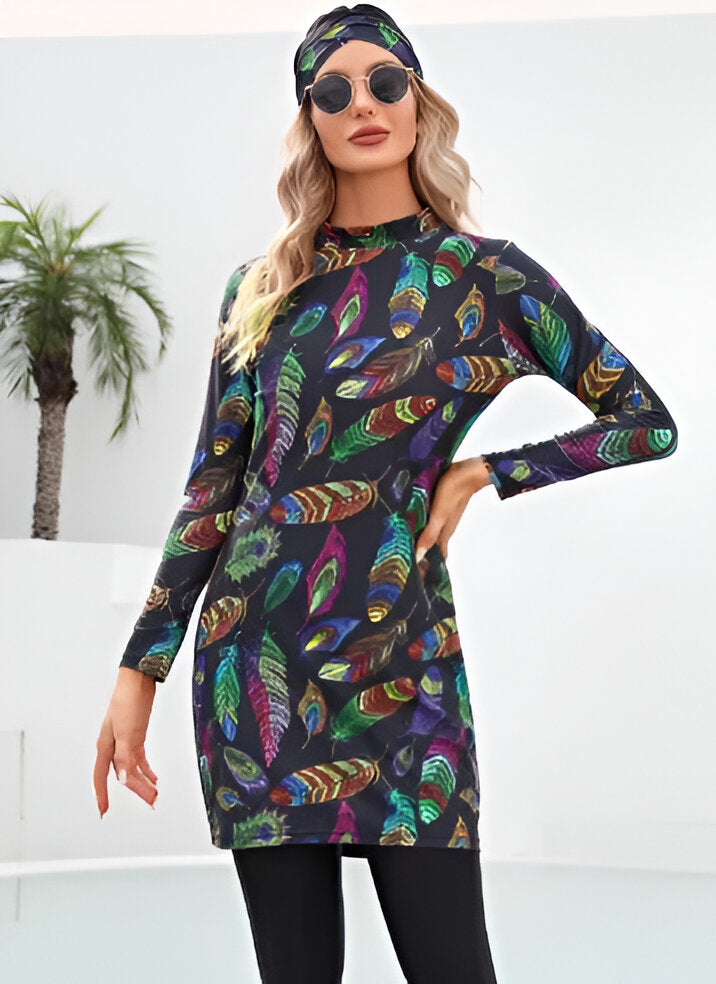 Une femme portant une robe longue noire à manches longues avec un imprimé de plumes multicolores et un foulard assorti sur la tête.  Elle porte également des lunettes de soleil.  La robe est parfaite pour un look élégant et confortable.