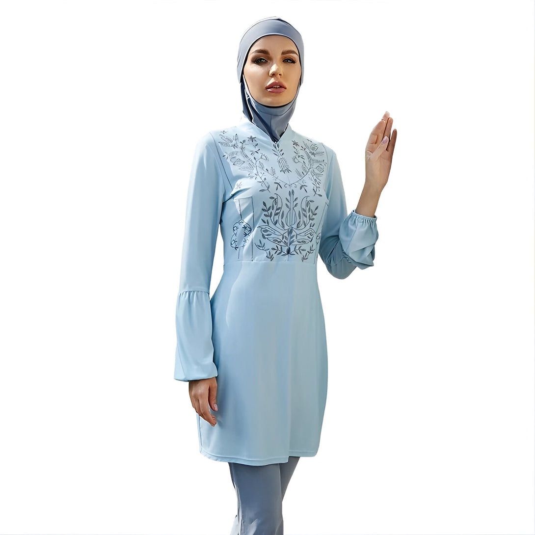 Une femme portant un maillot de bain musulman bleu ciel avec des motifs floraux gris.