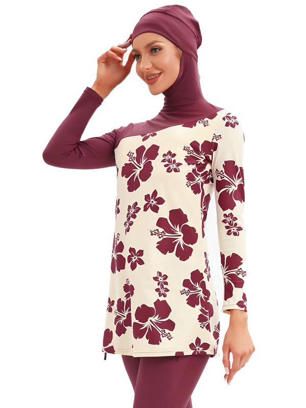 Une femme portant un maillot de bain musulman à manches longues avec un motif de fleurs hibiscus. Le maillot de bain est de couleur bordeaux et beige. La femme porte un hijab bordeaux assorti.