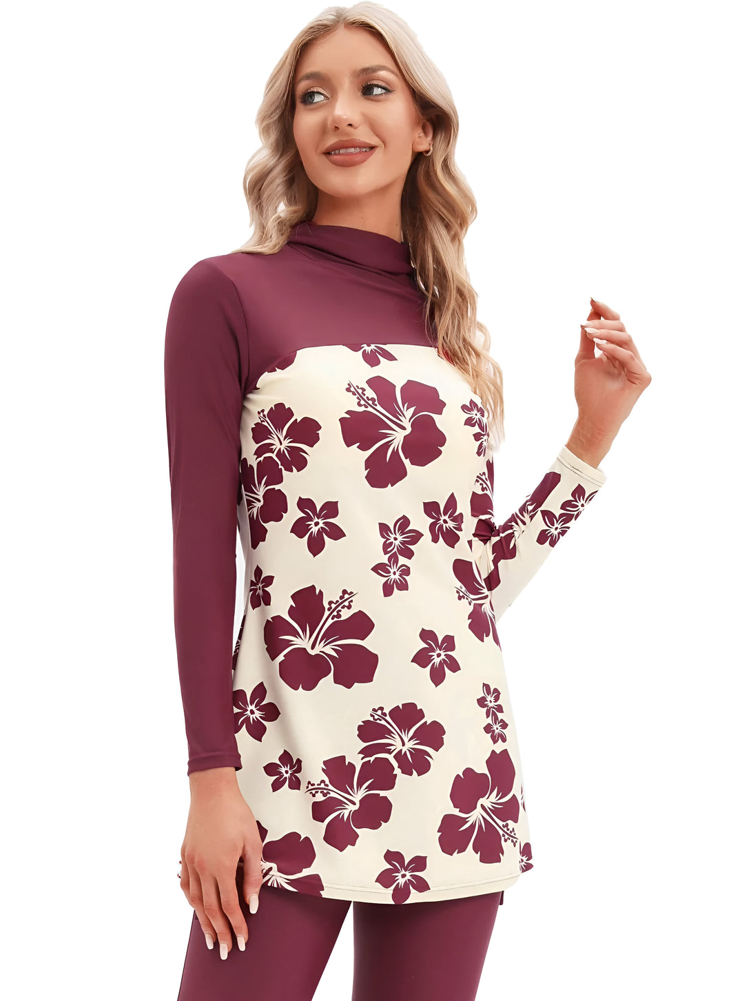 Une femme souriante porte un maillot de bain musulman à manches longues avec un motif floral rouge sur un fond crème. Le maillot de bain est composé d'un haut et d'un pantalon assortis.