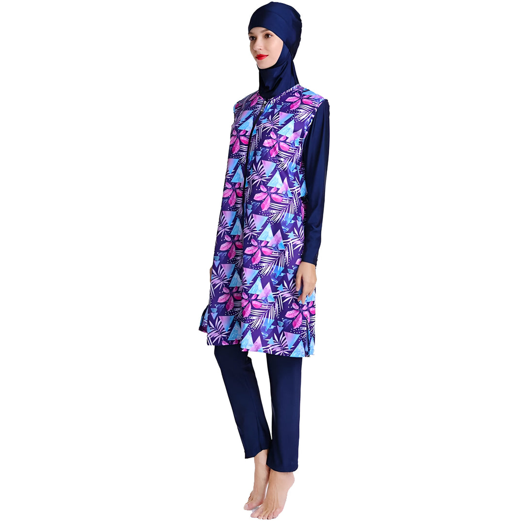 Une femme portant un maillot de bain musulman bleu marine à motifs floraux. Le maillot de bain comprend une tunique à manches longues et un pantalon long.