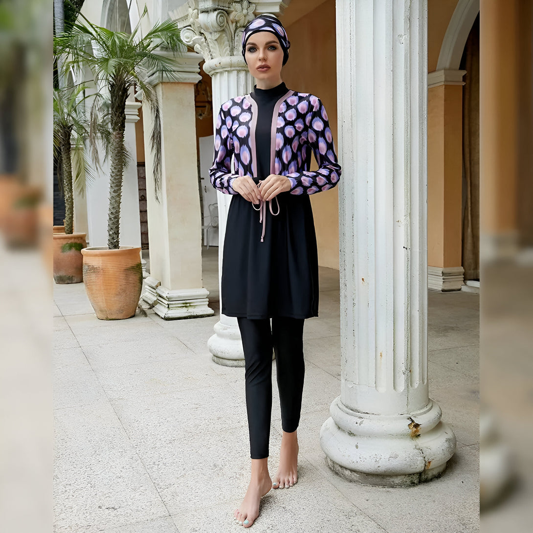 Une femme portant un maillot de bain musulman noir et violet avec une jupe, un pantalon et un hijab. Elle est debout devant des colonnes blanches.