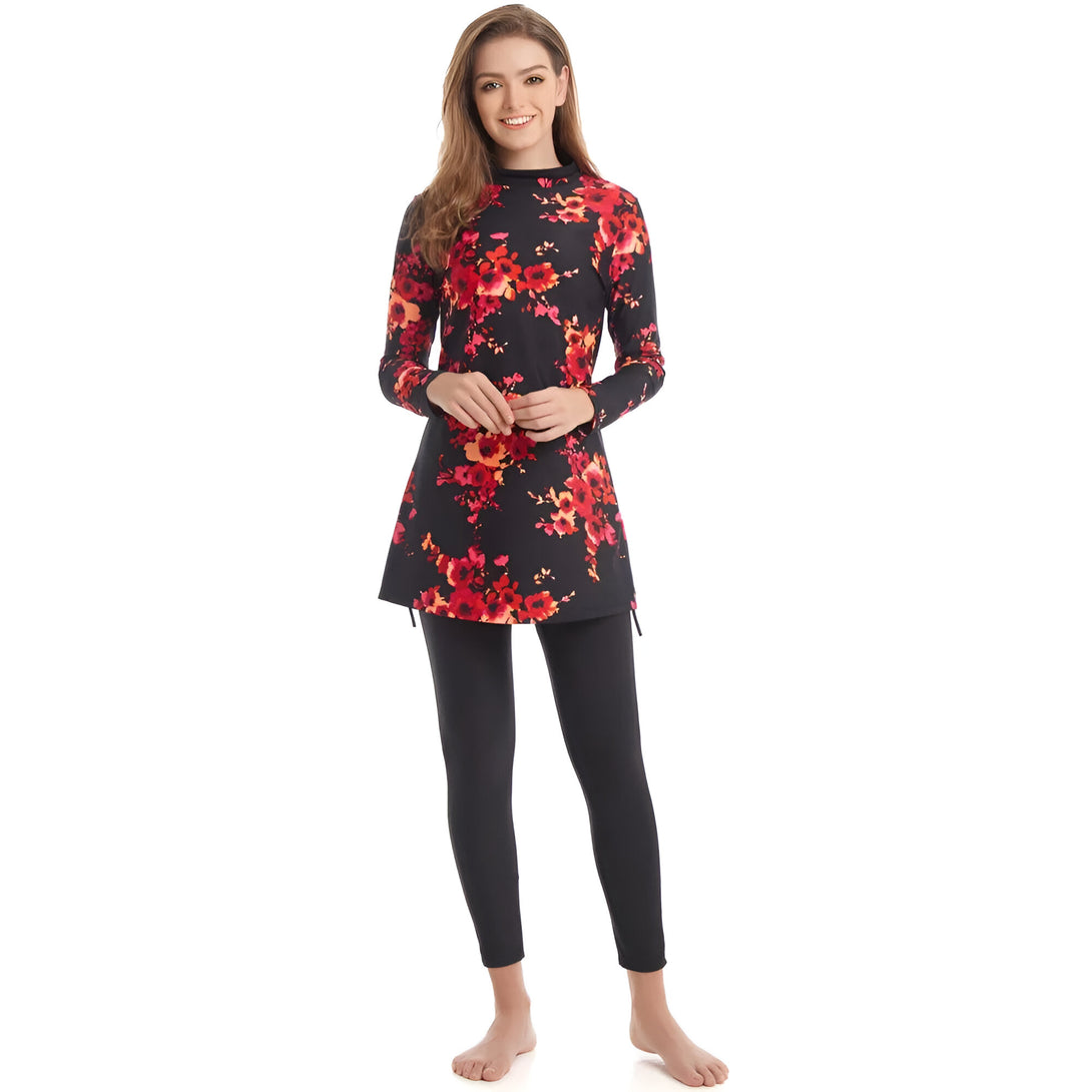 Une femme porte un maillot de bain musulman noir à fleurs rouges. Le maillot de bain a des manches longues et une jupe longue. La femme sourit à la caméra.