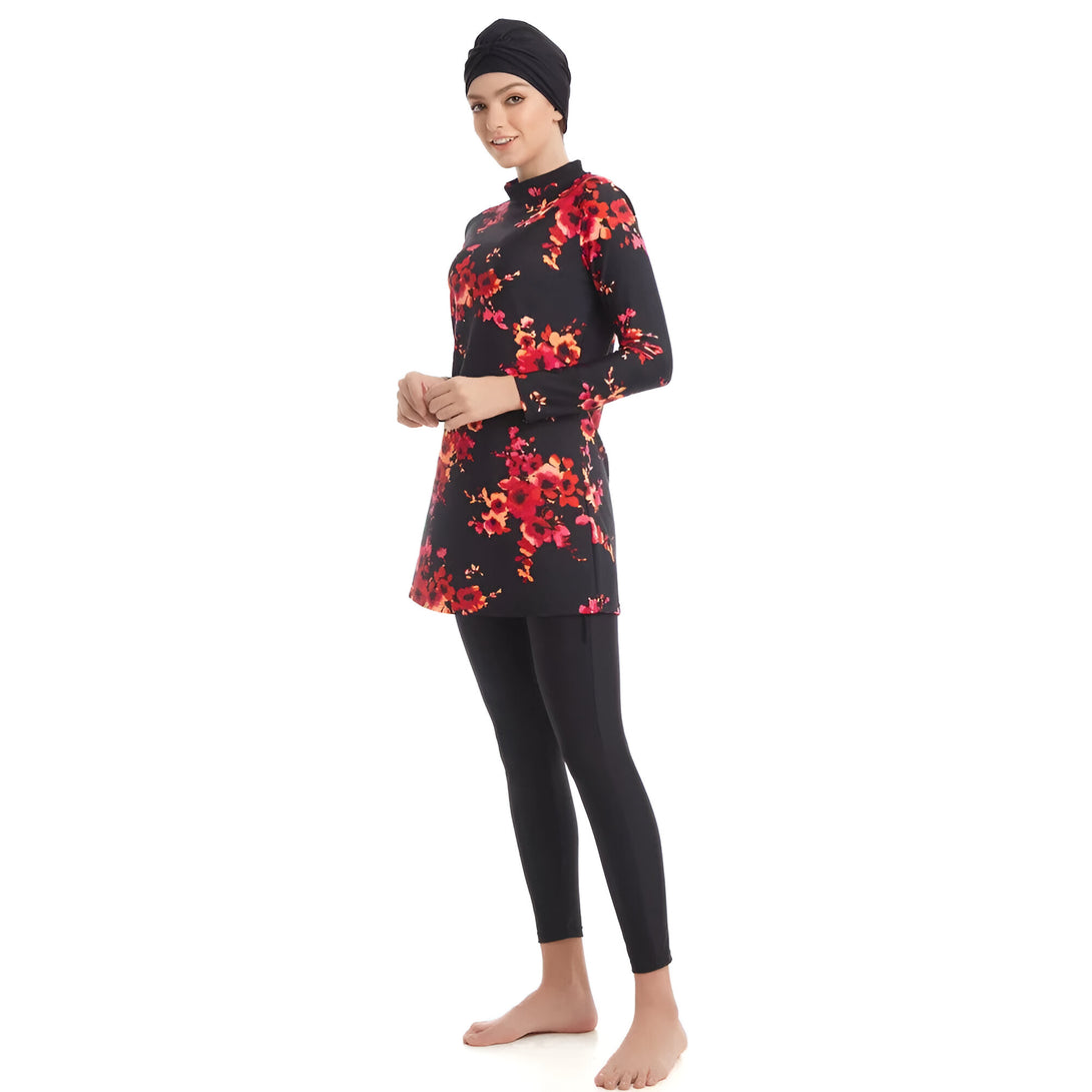 Une femme portant un maillot de bain musulman noir à fleurs rouges. Le maillot de bain comprend une tunique à manches longues et un pantalon long. Elle porte également un hijab noir.