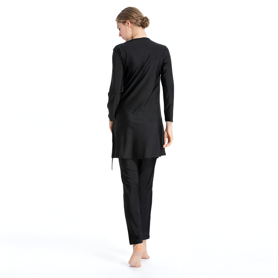 Une femme portant un maillot de bain musulman noir, avec une tunique à manches longues et un pantalon long.