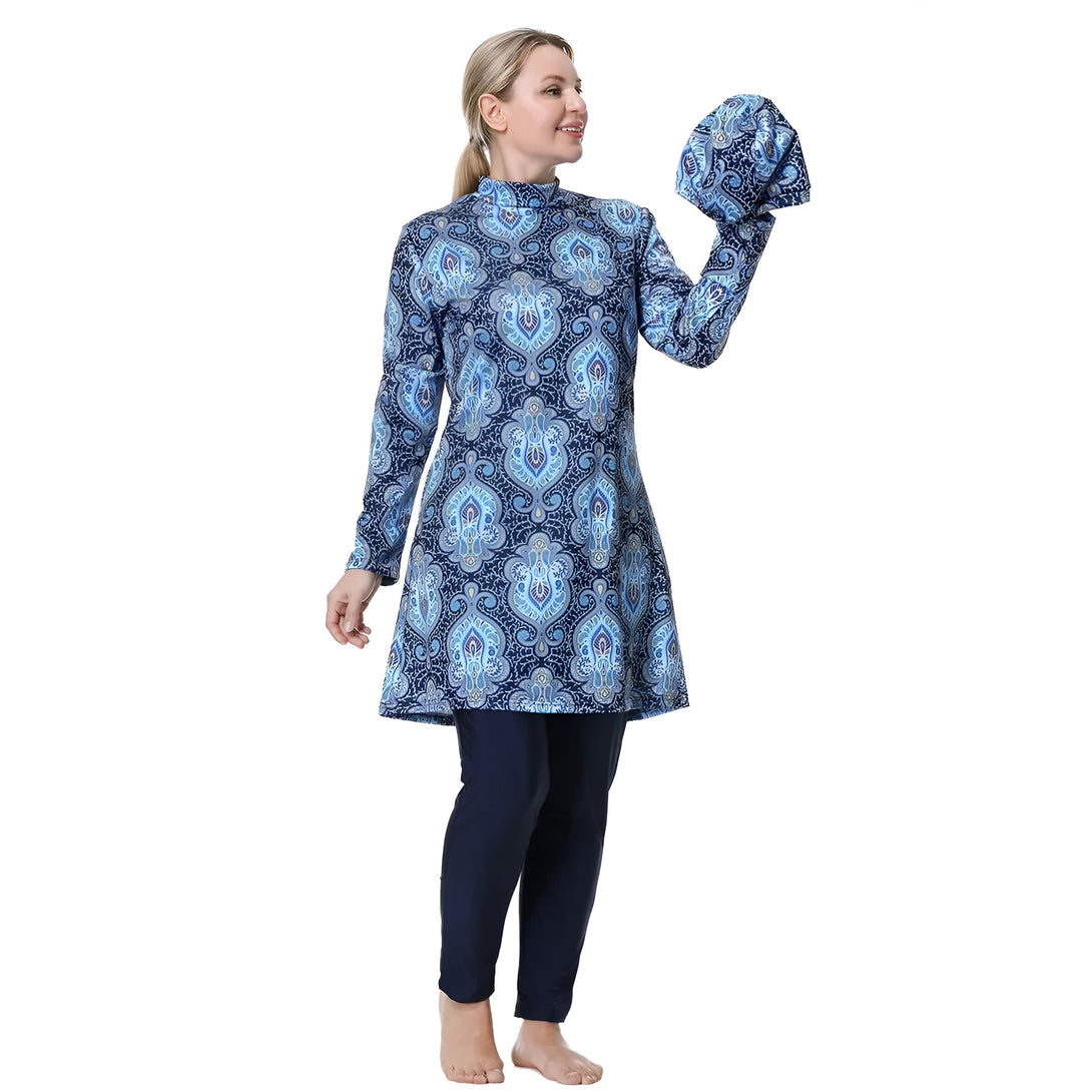 Une femme portant un maillot de bain musulman bleu et noir à motifs. Le maillot de bain comprend une tunique à manches longues et un pantalon long. La femme porte également un foulard assorti.