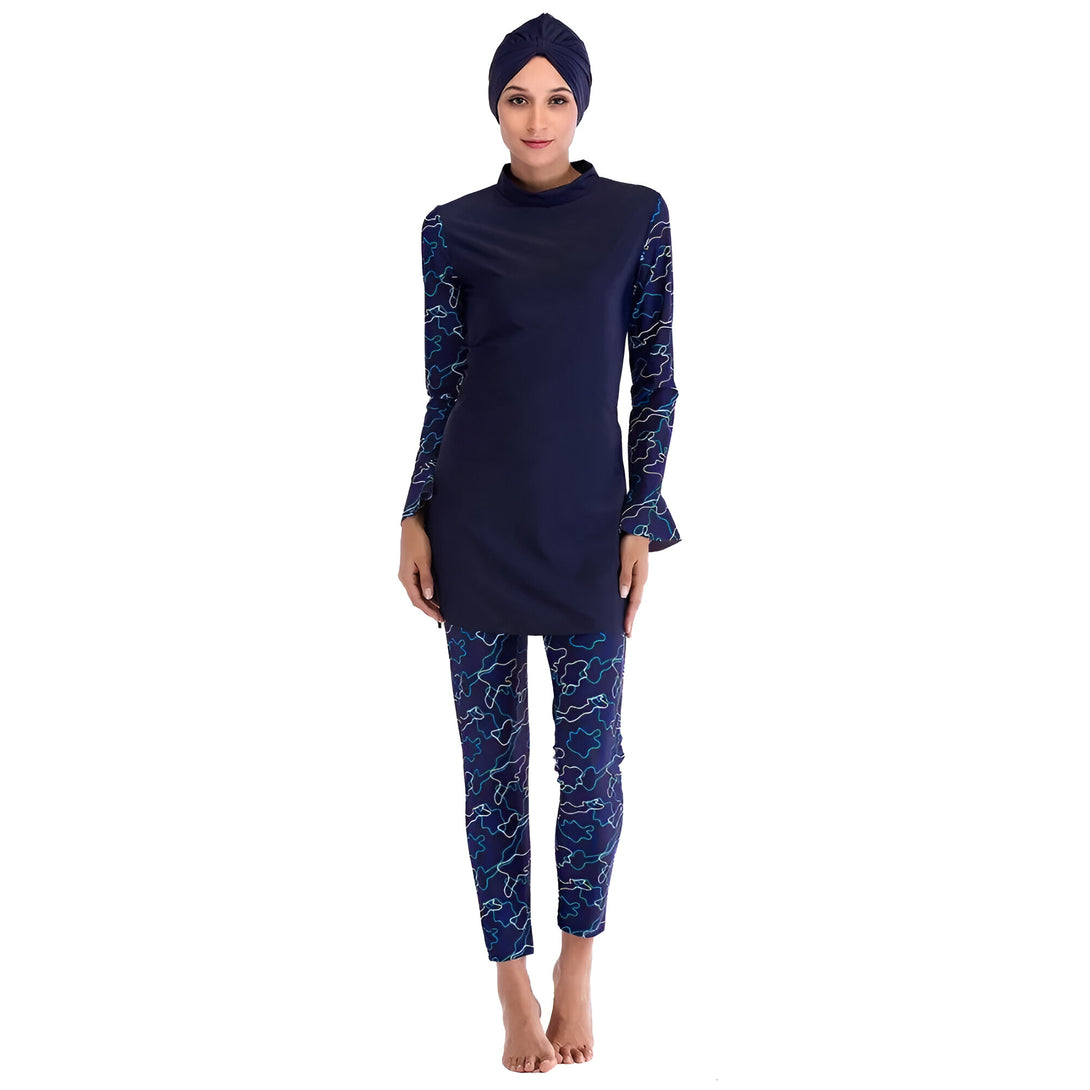 Femme portant un maillot de bain musulman bleu marine avec un pantalon imprimé. Le maillot de bain est à manches longues et a un col rond. La femme porte un hijab bleu marine.