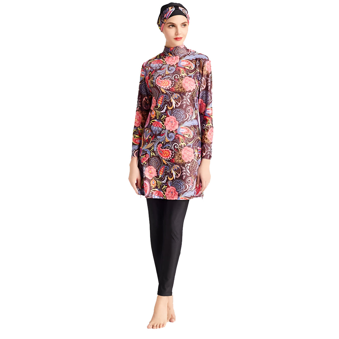 Une femme portant un maillot de bain musulman avec un motif floral coloré et un hijab assorti.  Le maillot de bain comprend une tunique à manches longues et un pantalon long.  Le modèle pose sur un fond blanc.