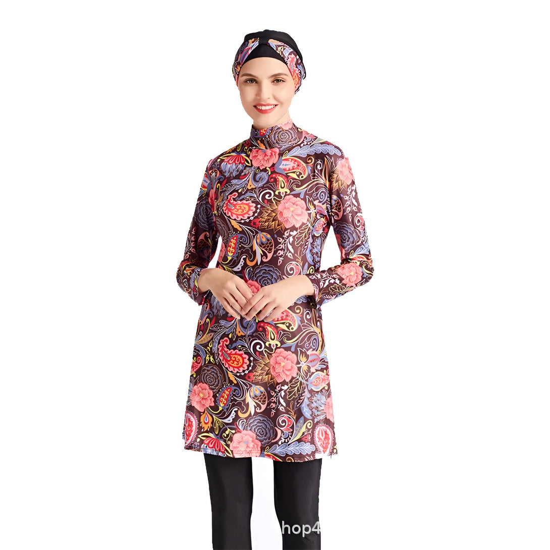 Une femme porte un maillot de bain musulman à manches longues avec un motif floral coloré. Le maillot de bain est brun foncé avec des fleurs roses, jaunes, bleues et rouges. La femme porte également un hijab noir.