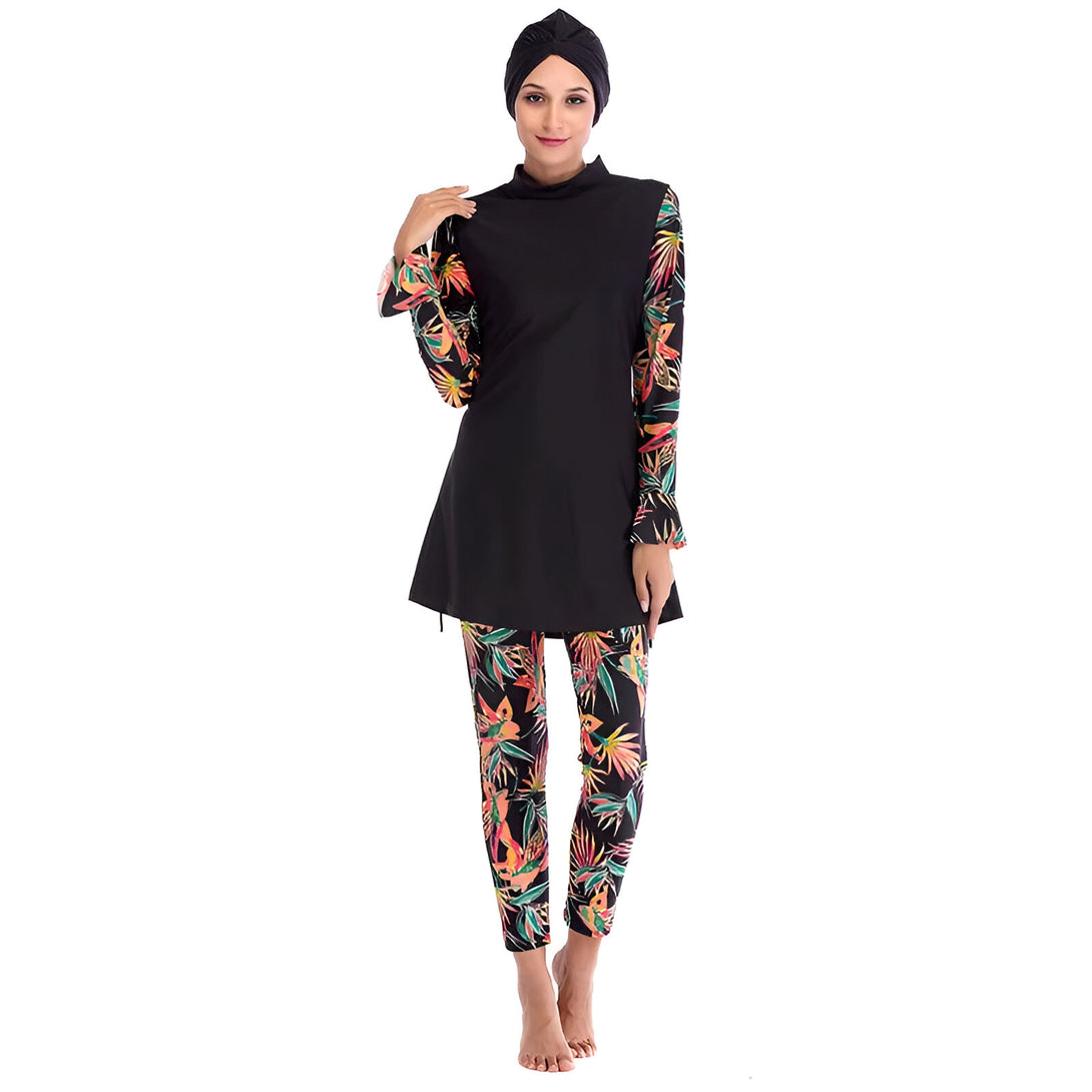 Une femme porte un maillot de bain musulman noir avec des manches longues et un pantalon à imprimé floral. Le maillot de bain est conçu pour les femmes musulmanes qui souhaitent se couvrir en toute modestie tout en nageant.