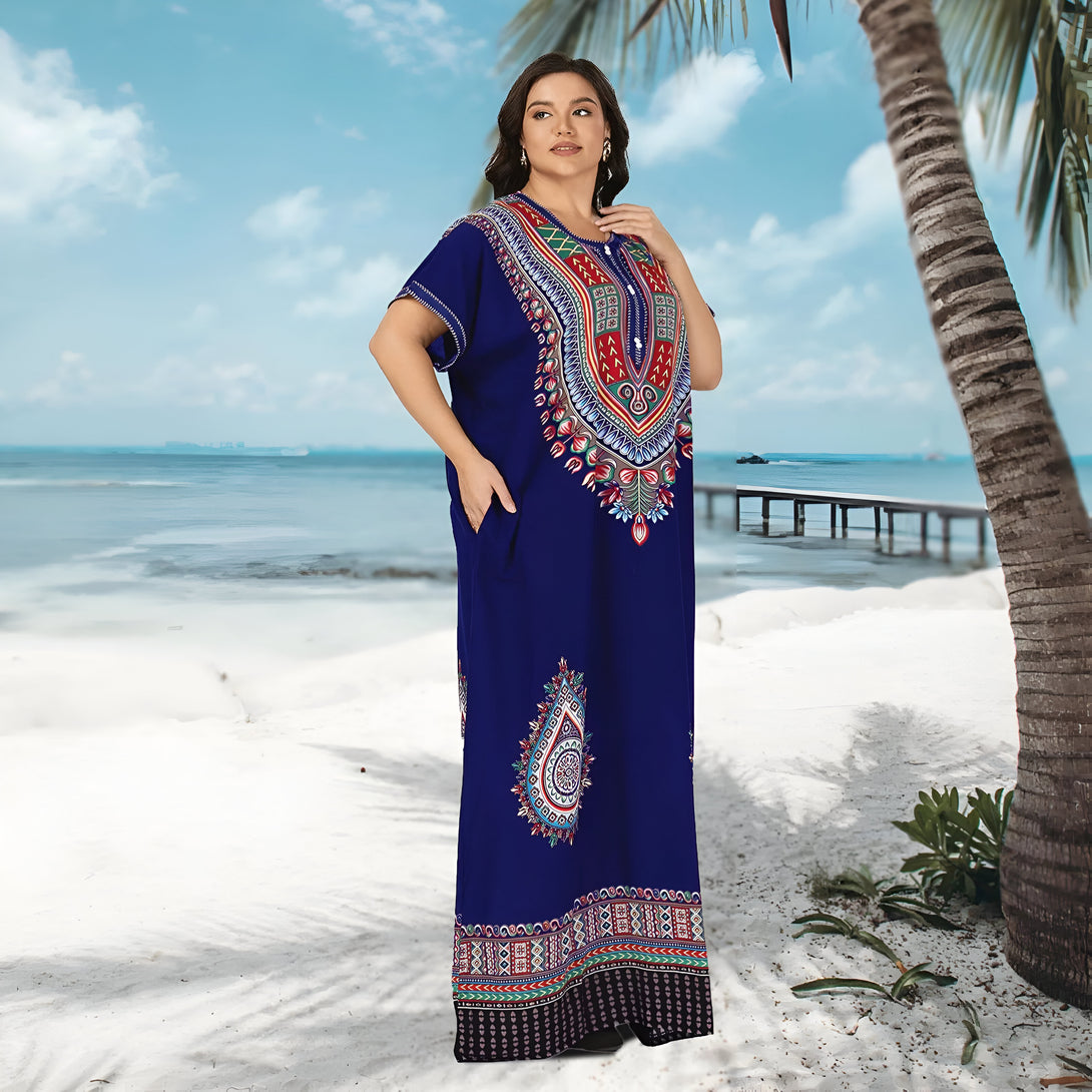 Une femme portant une longue robe bleue à manches courtes avec des motifs ethniques sur une plage tropicale. La robe est à la fois élégante et confortable pour toutes les occasions.