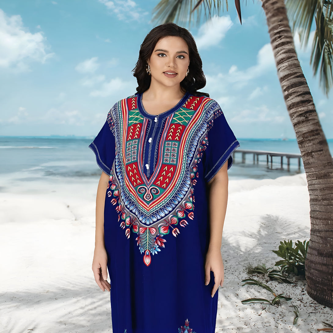 Une femme portant une robe bleue avec un motif ethnique sur la plage. La robe est ample et confortable, idéale pour l'été. La femme semble détendue et à l'aise.