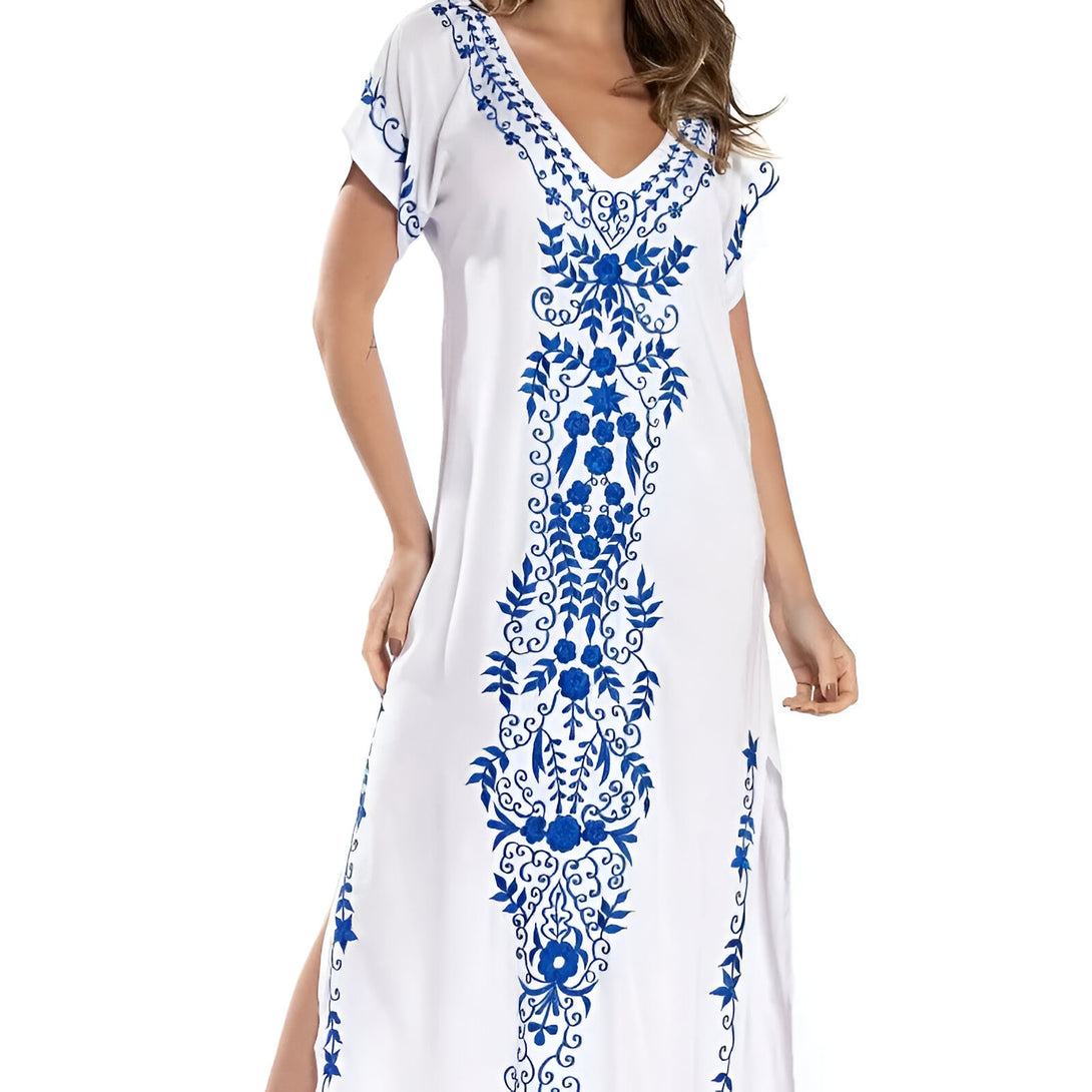 Robe blanche longue avec des broderies bleues de fleurs et de feuilles. La robe est élégante et confortable. Elle est parfaite pour les occasions spéciales ou pour un look décontracté.