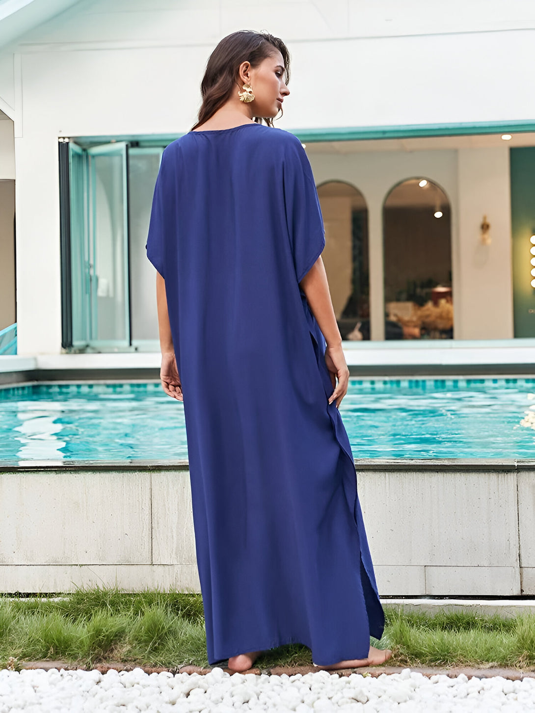 Une femme portant une longue robe bleue près d'une piscine. La robe est ample et à manches courtes. Elle est parfaite pour les occasions spéciales ou pour un look décontracté.